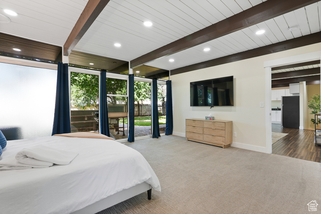 Carpeted bedroom featuring beam ceiling, baseboards, freestanding refrigerator, recessed lighting, and floor to ceiling windows