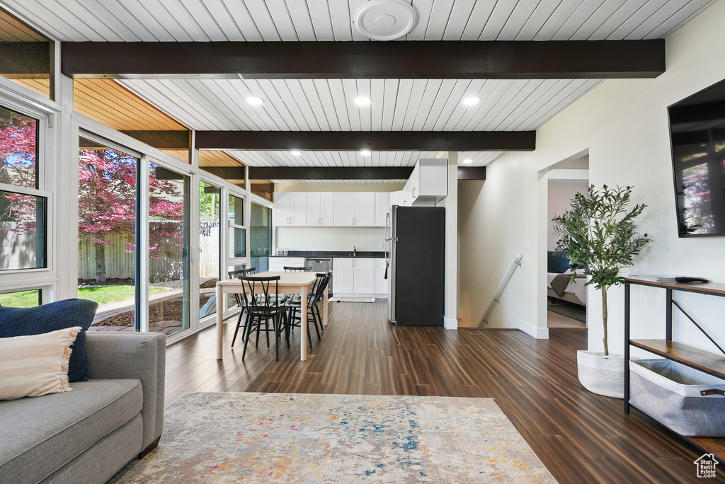 Dining area featuring dark wood-style flooring, baseboards, wood ceiling with exposed beams, and recessed lighting