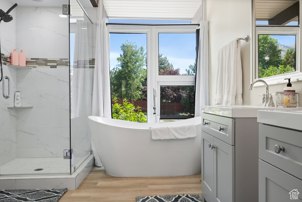 Bathroom featuring a marble finish shower, a freestanding bath, vanity, and wood finished floors