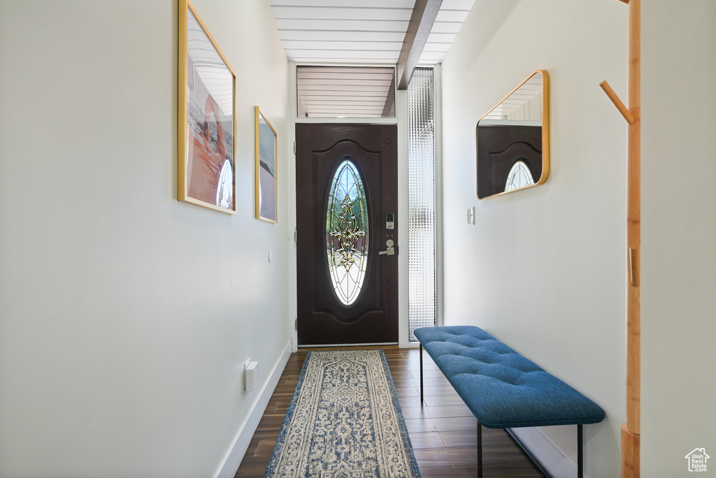 Doorway to outside featuring dark wood finished floors, baseboards, and beam ceiling