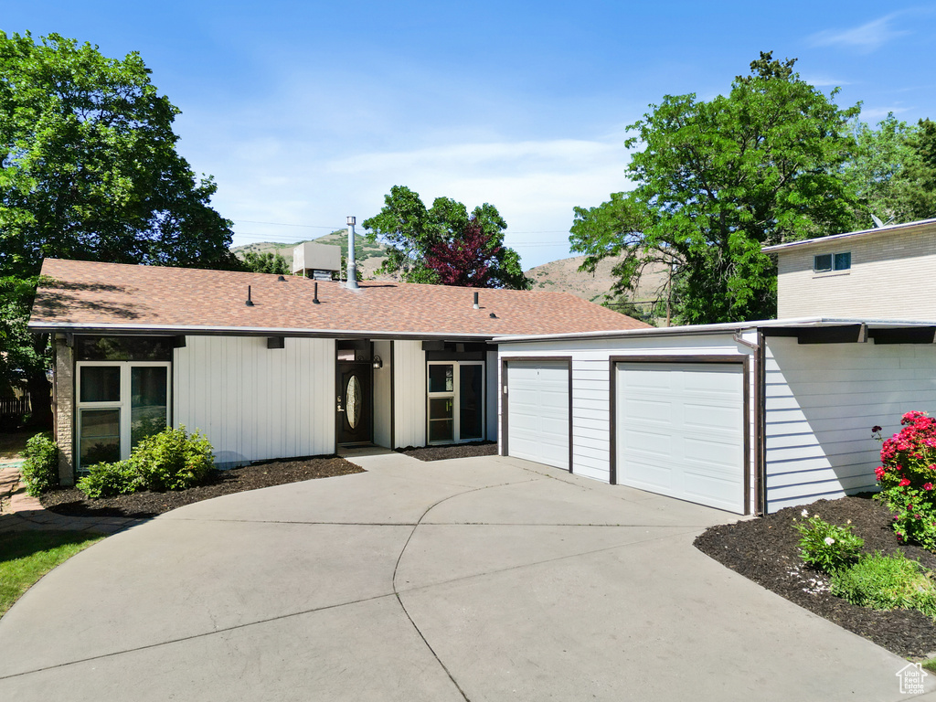 View of front of property with concrete driveway, an attached garage, and roof with shingles