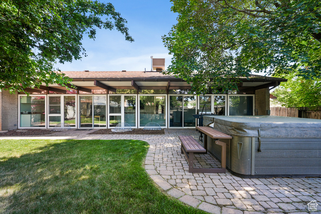 Rear view of house featuring a hot tub and a patio area