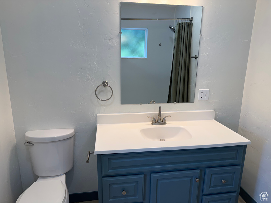 Bathroom with toilet, vanity, and a shower with curtain