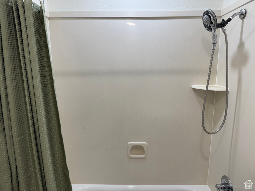 Bathroom view of shower / bath combo with shower curtain