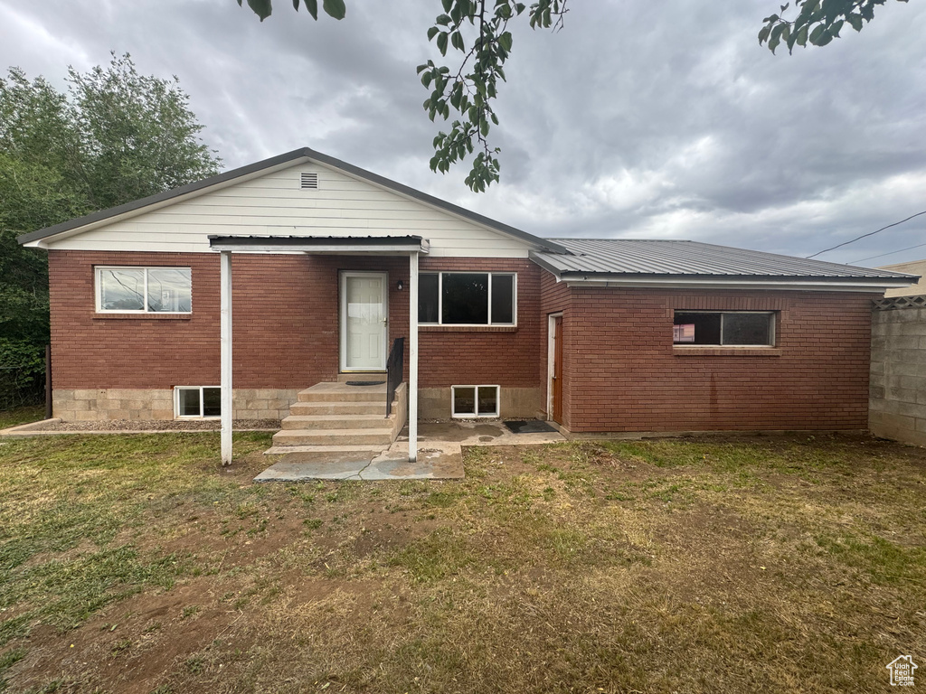 Back of house with a lawn, brick siding, and entry steps
