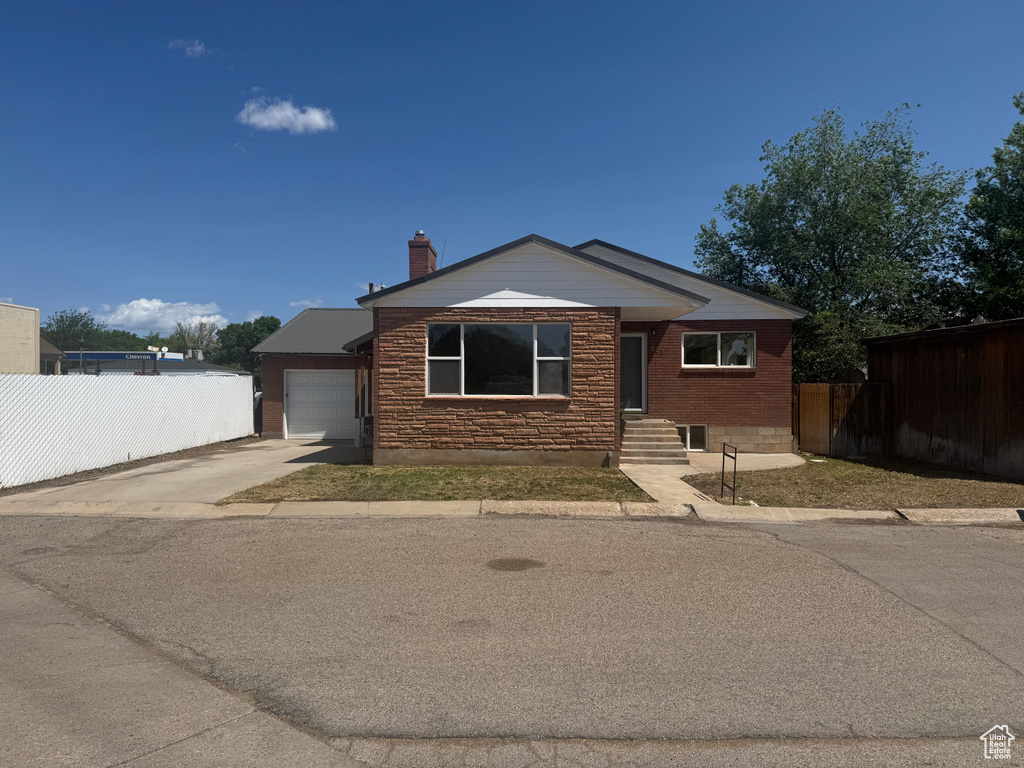 View of front facade with concrete driveway, a chimney, and a garage