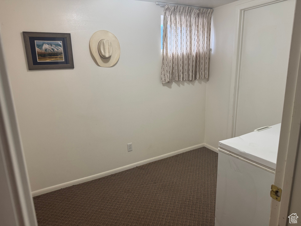 Unfurnished room with dark carpet and baseboards