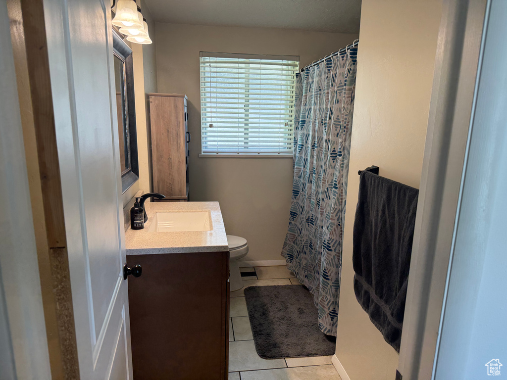 Full bathroom with vanity, tile patterned floors, toilet, baseboards, and a shower with curtain