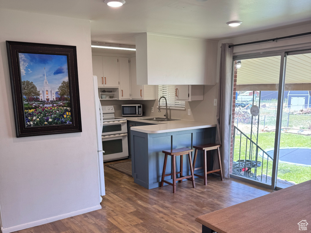 Kitchen with double oven range, stainless steel microwave, light countertops, a sink, and a peninsula