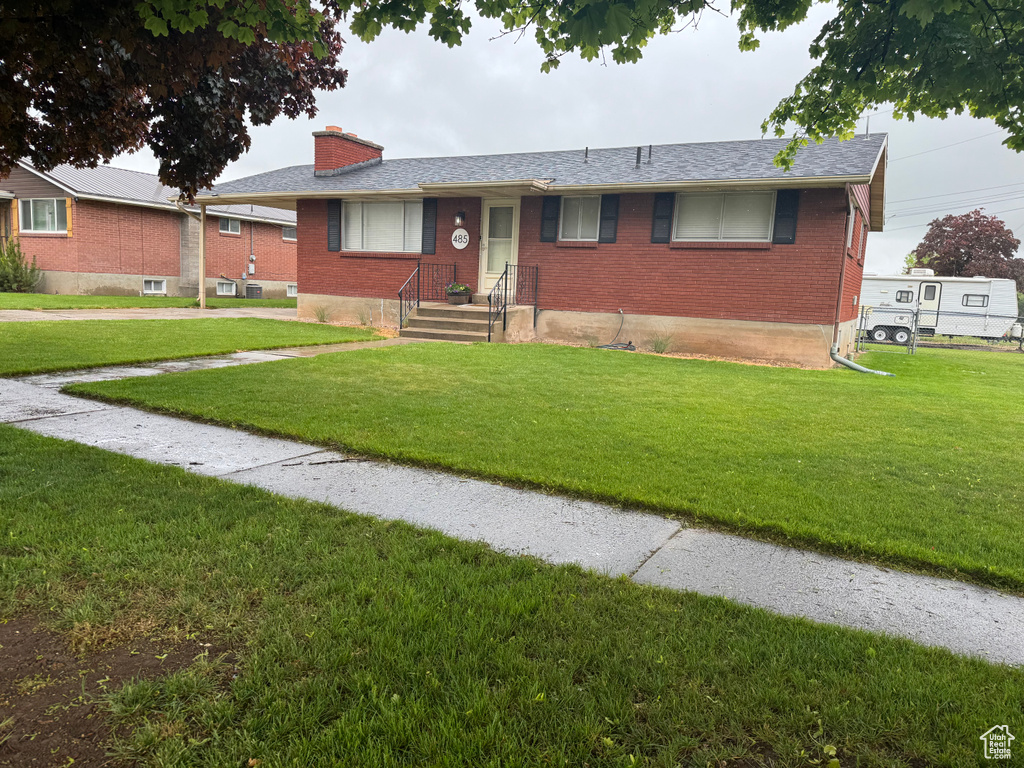 Single story home with brick siding, a chimney, and a front lawn