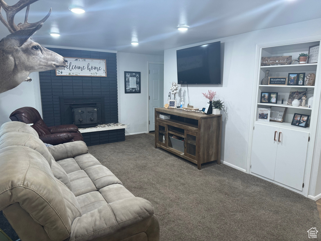 Living area featuring dark carpet, baseboards, and a brick fireplace