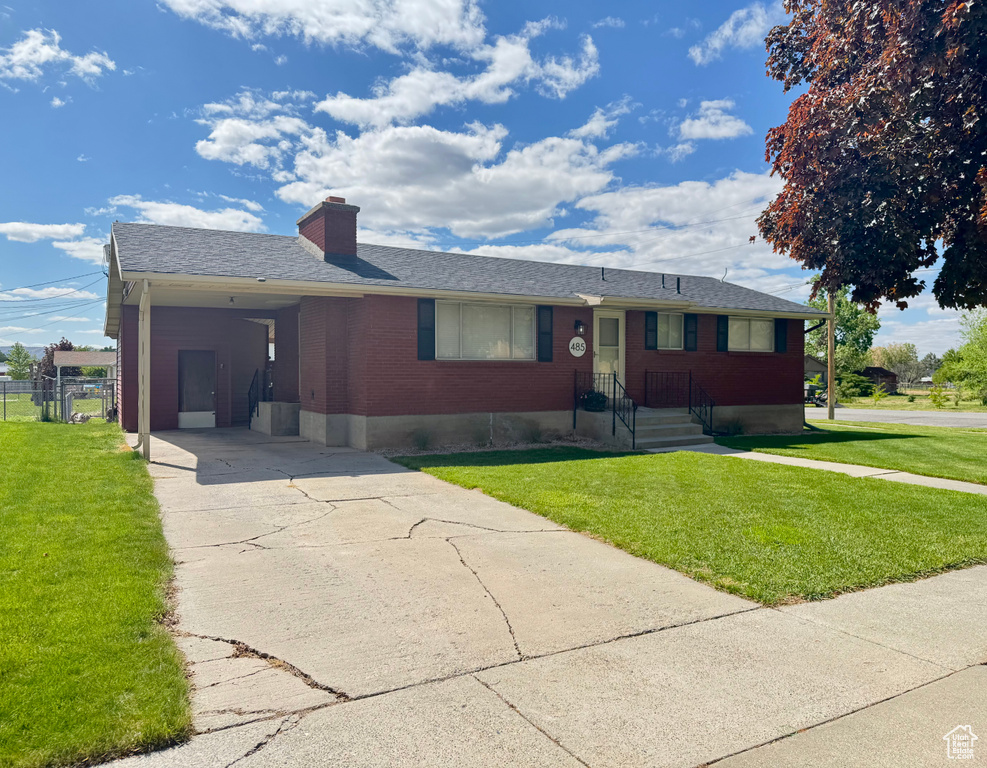 Single story home with brick siding, concrete driveway, a front yard, and a chimney