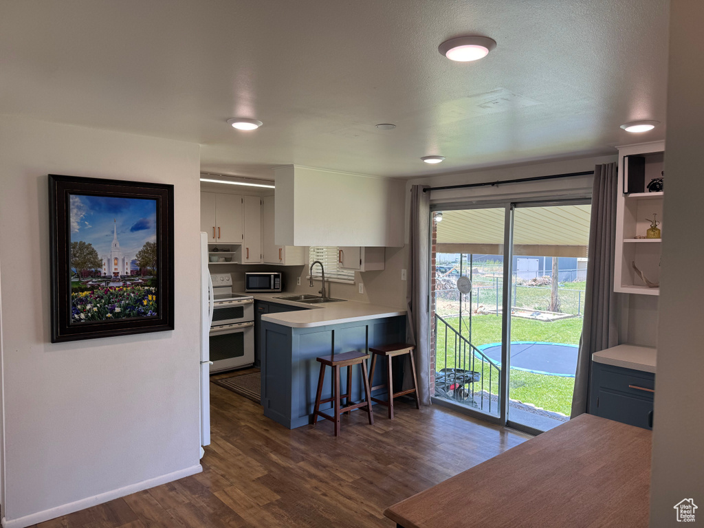 Kitchen featuring range with two ovens, stainless steel microwave, a sink, dark wood finished floors, and light countertops