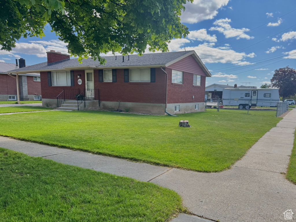 View of front of property with brick siding, a front lawn, and a chimney