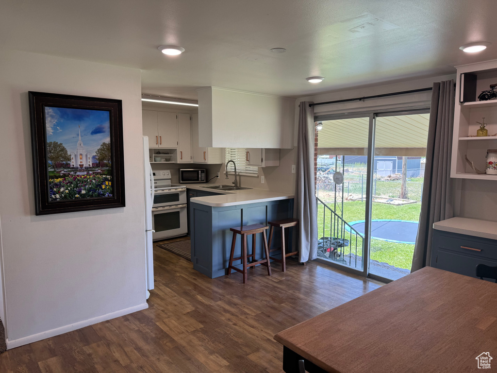 Kitchen featuring range with two ovens, stainless steel microwave, a sink, dark wood finished floors, and light countertops