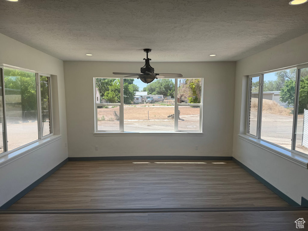 Unfurnished dining area featuring wood finished floors, a textured ceiling, recessed lighting, a ceiling fan, and baseboards