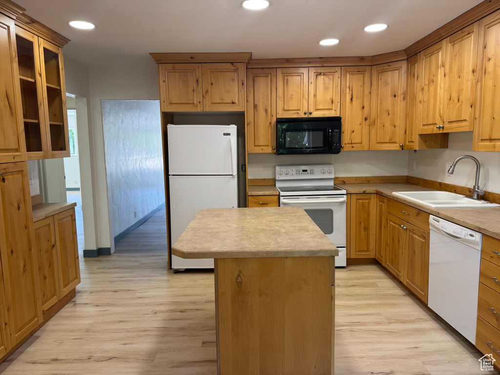 Kitchen featuring white appliances, a sink, light wood-style floors, a kitchen island, and recessed lighting