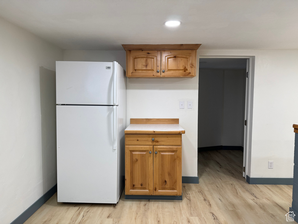 Kitchen featuring freestanding refrigerator, light wood-style flooring, baseboards, and light countertops