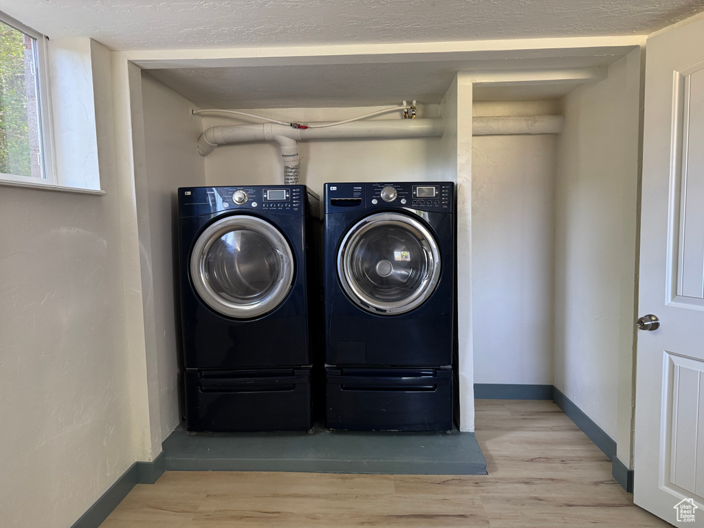 Laundry room with independent washer and dryer, wood finished floors, and baseboards