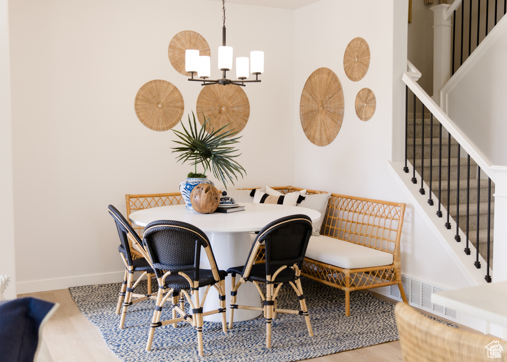 Dining space featuring wood finished floors, a chandelier, stairway, and baseboards