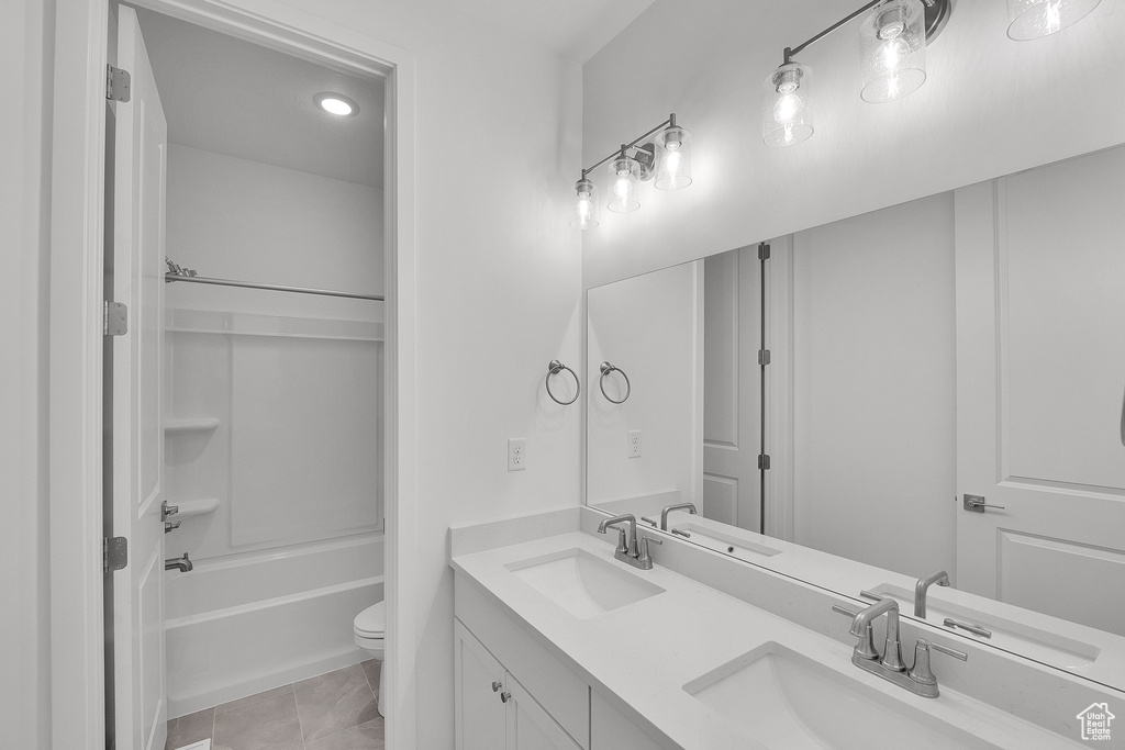 Full bathroom featuring double vanity, toilet, and washtub / shower combination