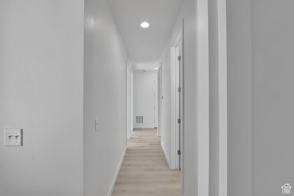 Hall with baseboards, light wood finished floors, and recessed lighting