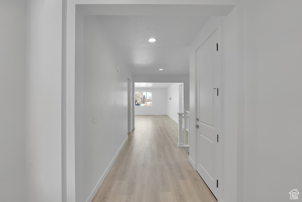Corridor with light wood-type flooring, recessed lighting, and baseboards