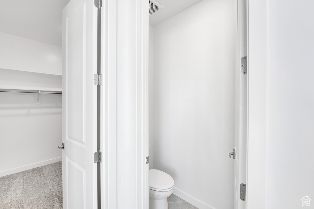 Bathroom featuring baseboards, toilet, and a walk in closet