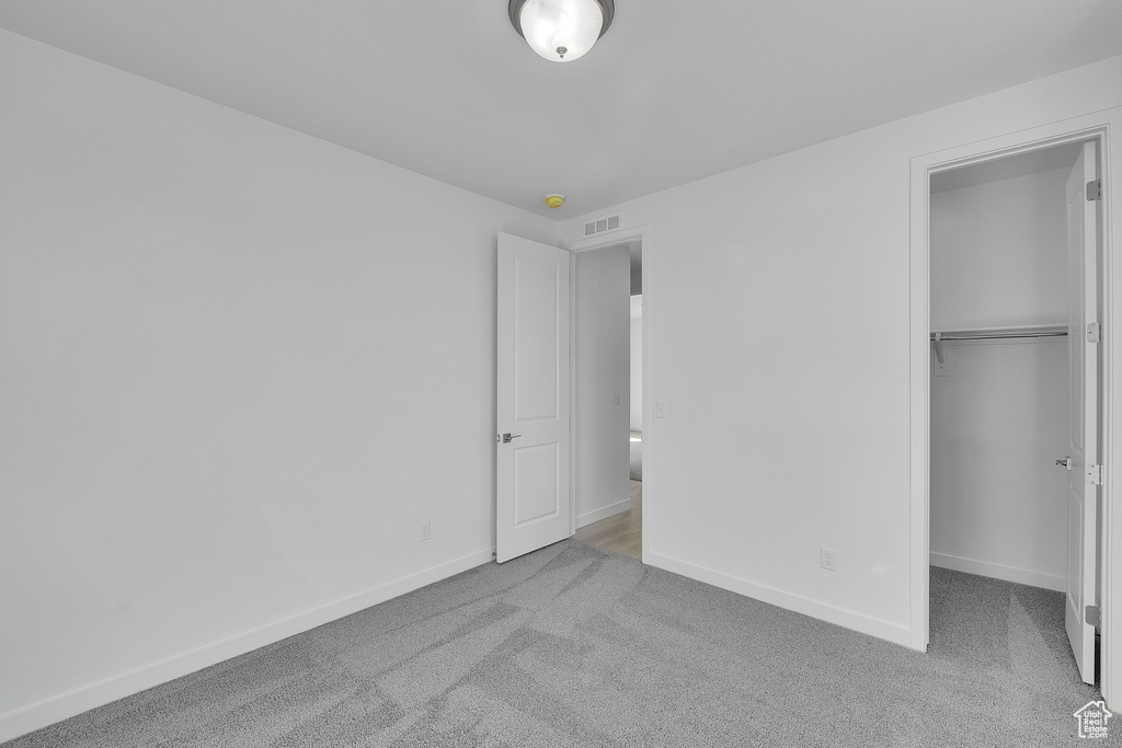 Unfurnished bedroom with carpet floors, baseboards, a closet, and a spacious closet