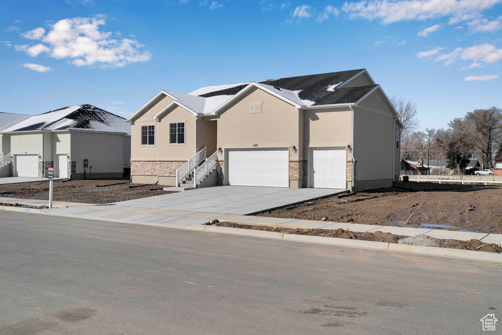 View of front of property featuring a garage, stucco siding, and driveway