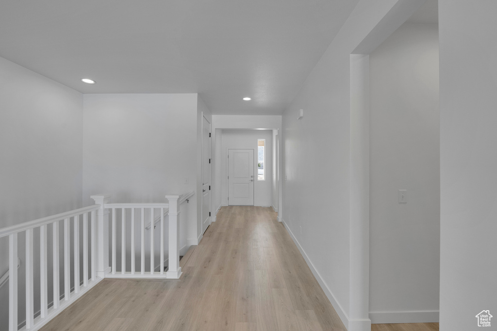 Corridor featuring light wood-style flooring, an upstairs landing, and recessed lighting