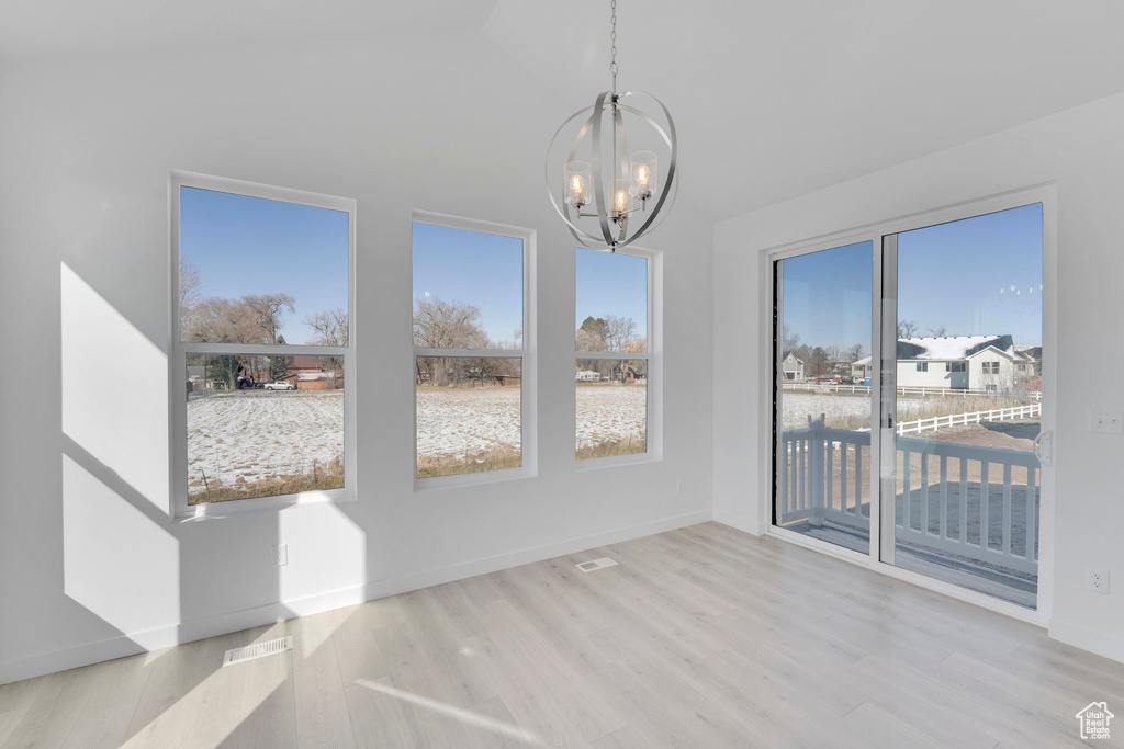 Unfurnished dining area featuring a chandelier, wood finished floors, baseboards, and high vaulted ceiling
