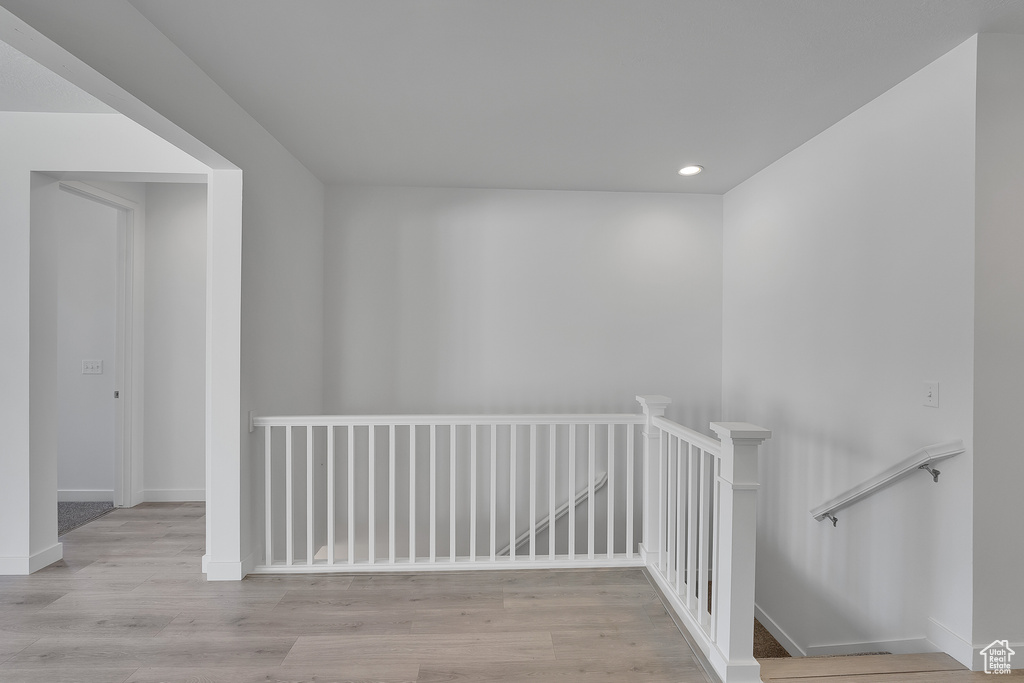 Corridor with an upstairs landing, recessed lighting, wood finished floors, and baseboards