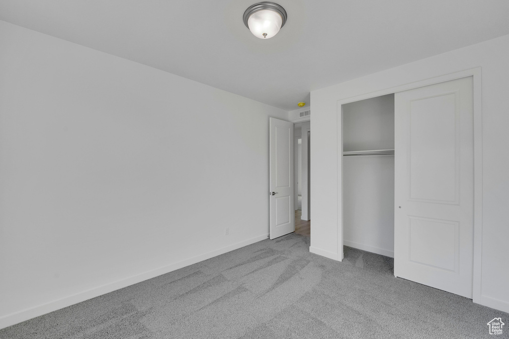 Unfurnished bedroom featuring carpet, a closet, and baseboards