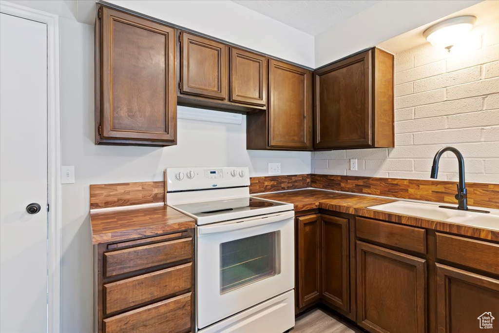 Kitchen featuring white range with electric stovetop, a sink, and butcher block countertops