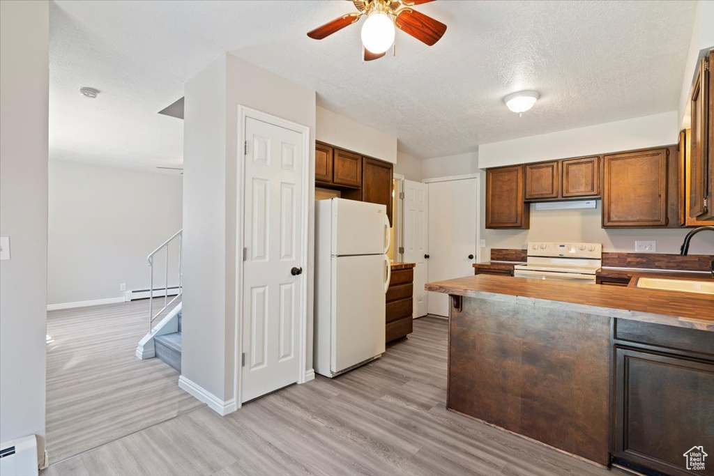 Kitchen with white appliances, a sink, baseboard heating, light wood finished floors, and a ceiling fan