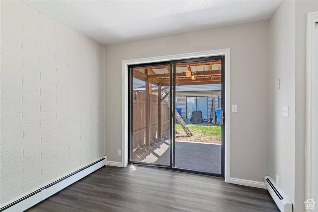 Spare room with baseboard heating, dark wood-style flooring, and baseboards