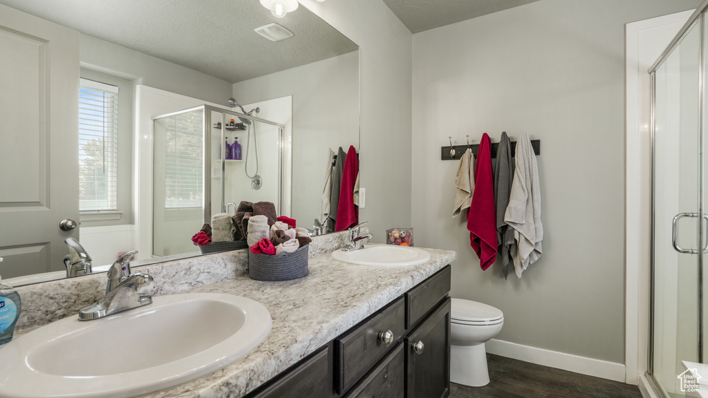 Full bath with a stall shower, wood finished floors, double vanity, toilet, and baseboards