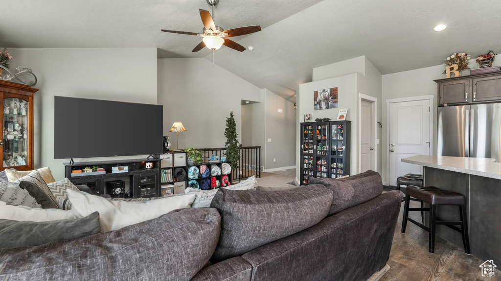 Living area featuring vaulted ceiling, ceiling fan, dark wood-style flooring, and baseboards