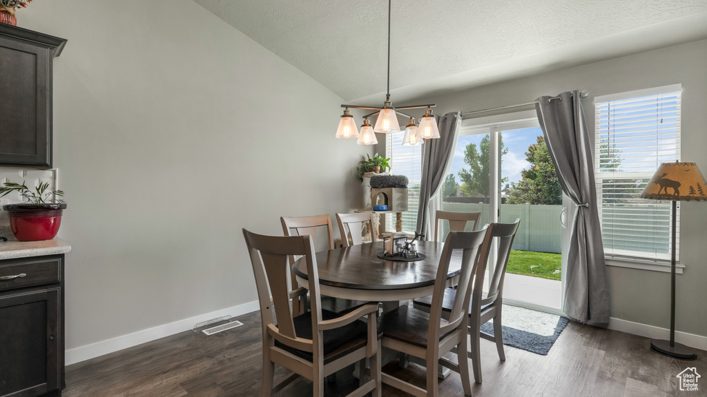 Dining area featuring baseboards, lofted ceiling, dark wood finished floors, and a textured ceiling