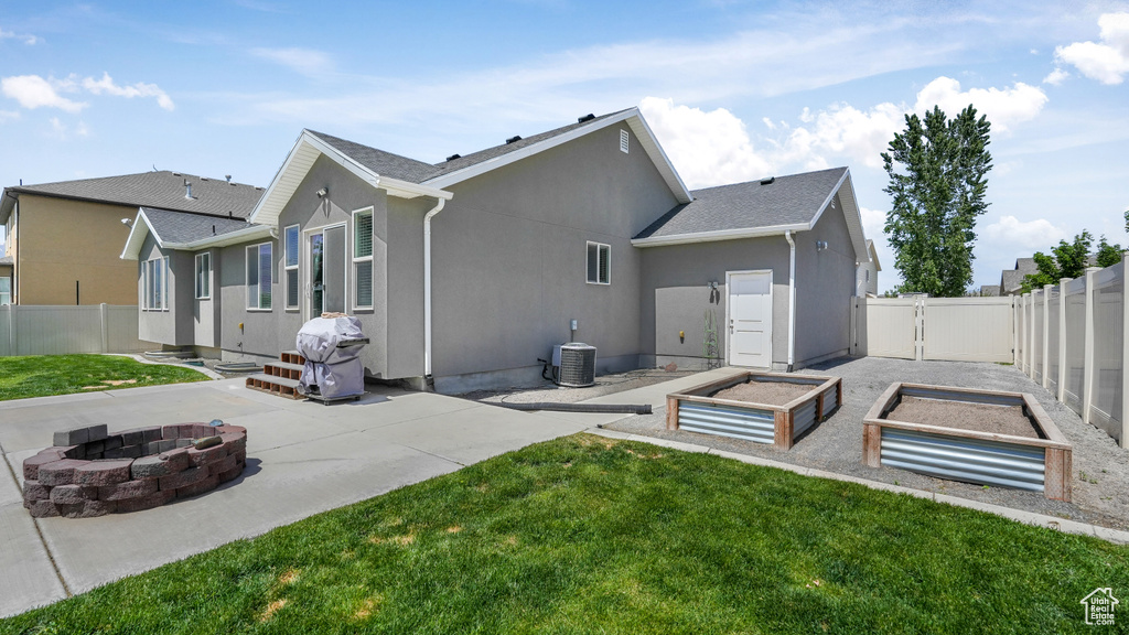 Rear view of property with an outdoor fire pit, a patio, a garden, central air condition unit, and stucco siding