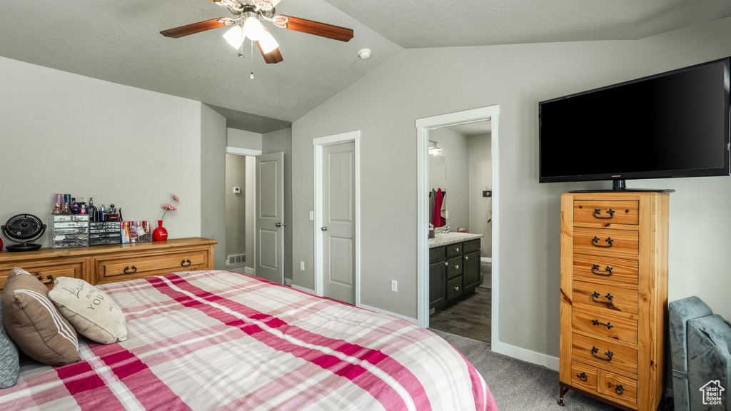 Bedroom with lofted ceiling, carpet flooring, baseboards, connected bathroom, and ceiling fan