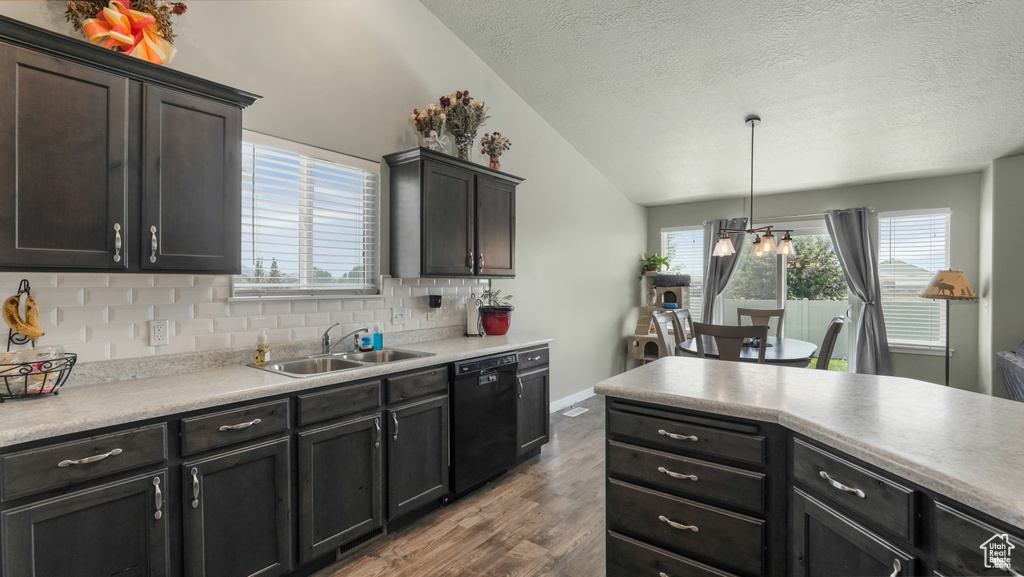 Kitchen featuring a sink, black dishwasher, wood finished floors, vaulted ceiling, and a textured ceiling