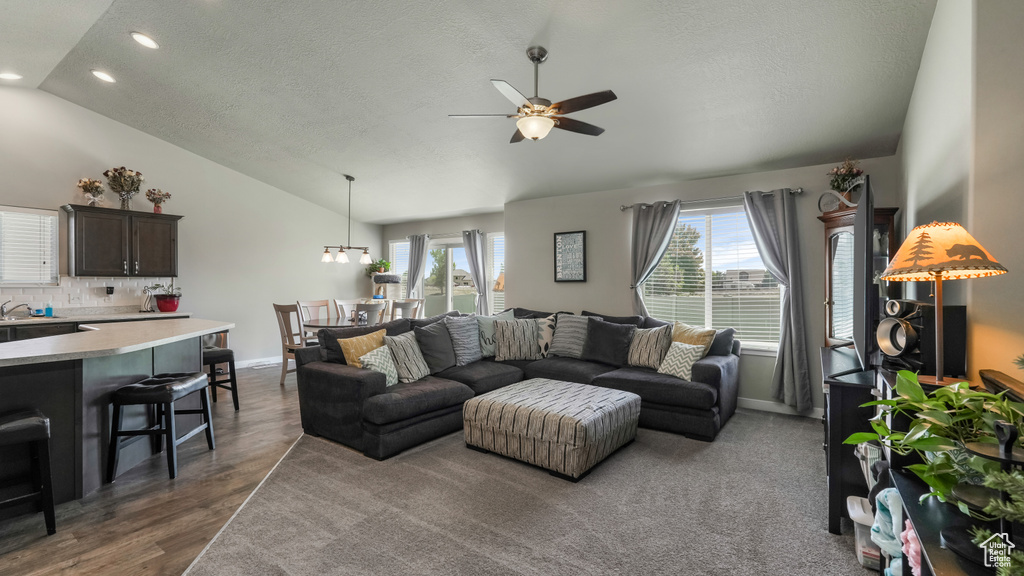 Living room featuring vaulted ceiling, ceiling fan, recessed lighting, a textured ceiling, and baseboards