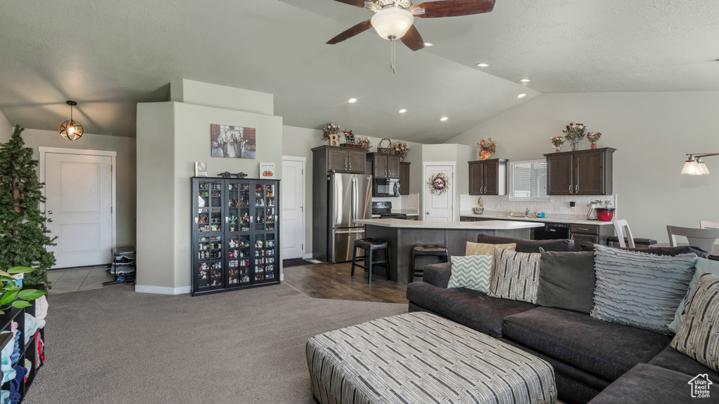 Carpeted living room featuring lofted ceiling, ceiling fan, and a sink