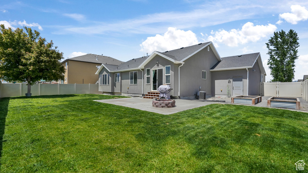Rear view of property with a patio area, stucco siding, central air condition unit, a vegetable garden, and a gate