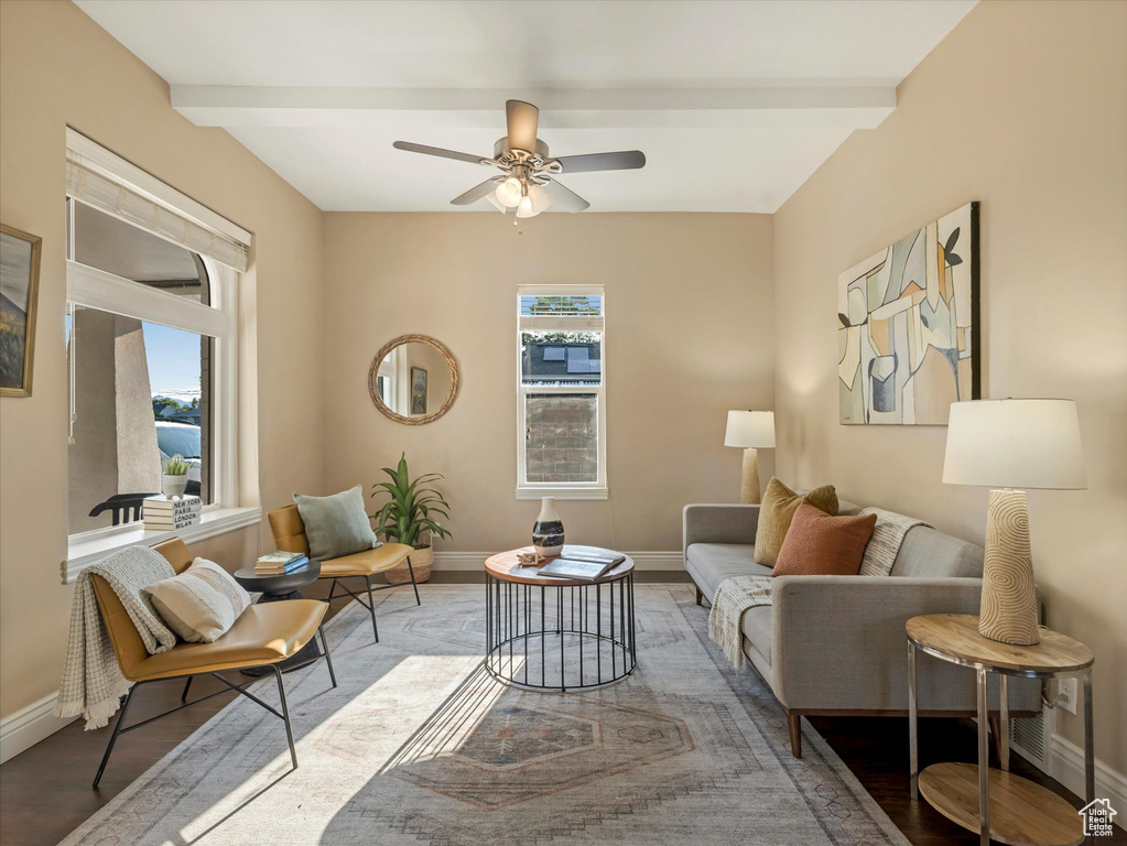 Living area with baseboards, beam ceiling, ceiling fan, and wood finished floors