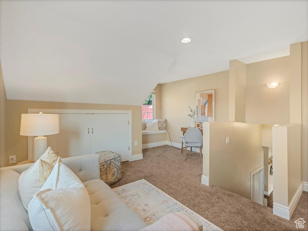 Carpeted living room featuring baseboards and vaulted ceiling