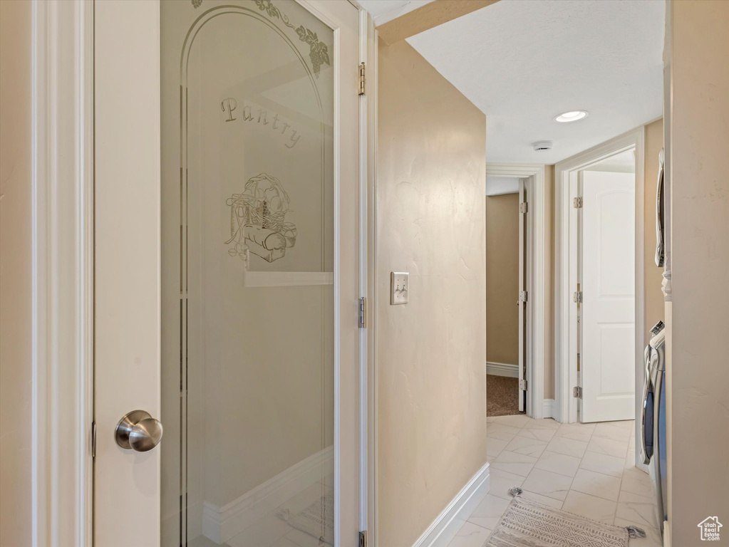 Hallway with light marble finish flooring, baseboards, and washer / clothes dryer