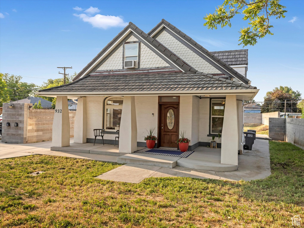 View of front of house with a porch, cooling unit, and brick siding